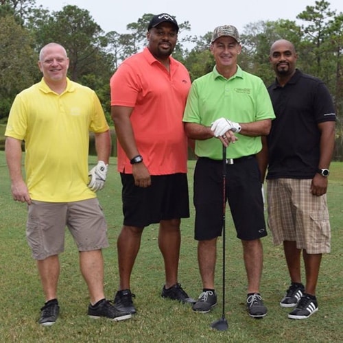 Four men in polo t-shirts on a golf course